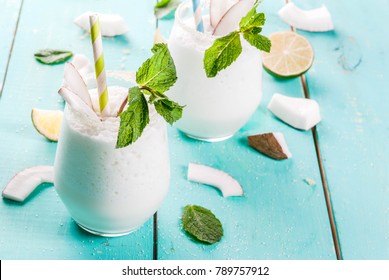 Summer refreshment drinks, cocktails. Frozen coconut mojito with lime and mint. Pina colada. On a light blue green wooden table with ingredients. Copy space