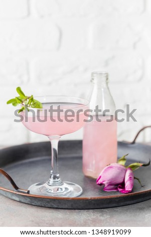 Summer refreshment drinks. Light pink rose cocktail, with rose wine on a white table. With rose flowers. Copy space