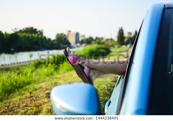 Summer road trip car vacation concept.
Woman legs out the windows in car above the clouds. Conceptual
freedom, travel and holidays image with copy
space.