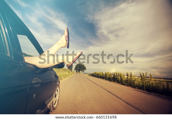 Summer\
road trip car vacation concept. Woman legs out the car windows ,\
conceptual freedom, travel and holidays\
image.