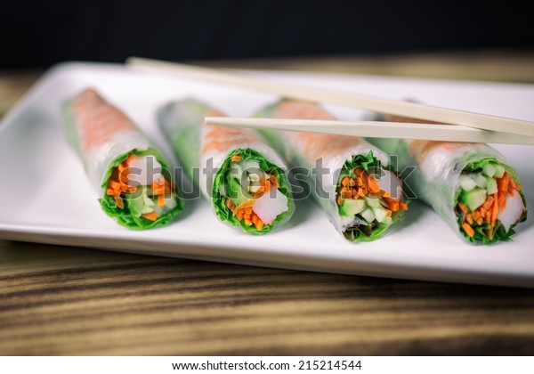 Summer roll sushi on a white rectangular plate with\
chopsticks. 