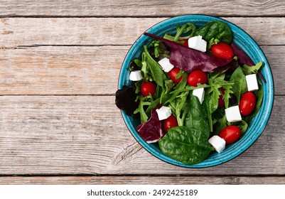 Summer salad with arugula, spinach, cherry tomatoes and cheese feta . Food background top view