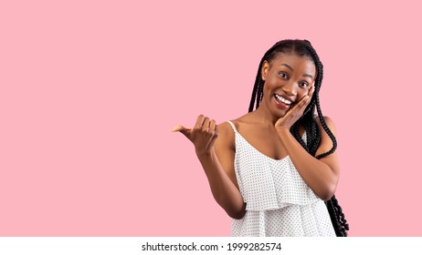 Summer sale. Emotional black lady pointing at blank space over pink studio background, banner design. Pretty African American woman in trendy clothes having special offer, advertising your product