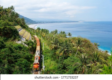 Summer Scene Of A Chu-Kuang Express Train Traveling On The Green Wooded Hillside Overlooking A White Sandy Beach On The Beautiful Coastline By The Blue Pacific Ocean, In Taimali, Taitung, Taiwan, Asia