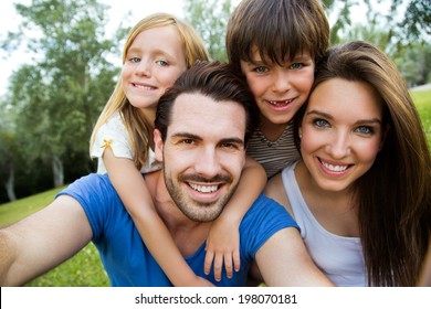 Summer scene of Happy young family taking selfies with her smartphone in the park - Powered by Shutterstock