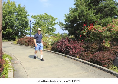 Summer scene of man walking down a sloped sidewalk near Beaverton, Oregon Sunset Transit Center.