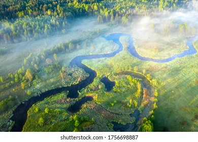 Summer scenery aerial view. Sunrise. Beautiful view on winding river surrounded meadow and forest. Early misty morning