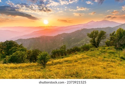 summer scenery mountain view from a highland hill to a beautiful sunset with green hills and slopes. Evening mountain landscape of amazing cloudy susnet above rocks