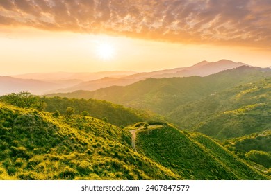 summer scenery mountain view from a highland hill to a beautiful sunset with green hills and slopes. Evening mountain landscape of amazing cloudy susnet above rocks