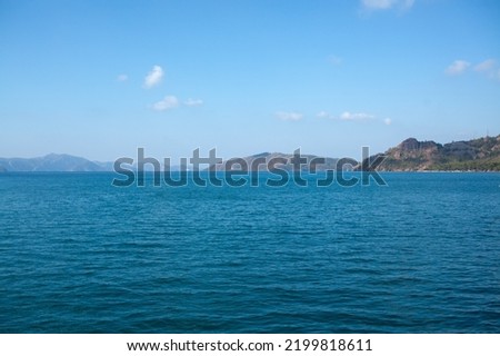 Summer seascape beautiful waves, blue sea water in sunny day. Sea bay with far hazed mountains on horizon. Fog in the mountains.