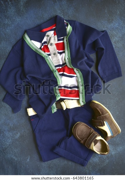 Summer set boys clothes in\
marine style on a dark blue slate,stone or concrete background.Top\
view.