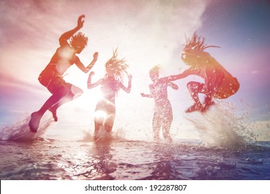 summer silhouettes of happy young people jumping in sea on the beach. vintage retro style with soft focus and sun flare