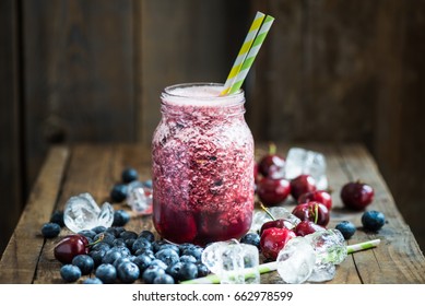 Summer Slushy from Blueberries, Cherries, Lemon and Ice with Ingredients nearby, on dark rustic background