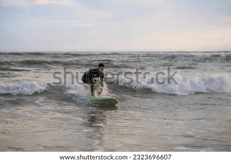 Summer Sport Activity. Young Handsome Man Surfing On The Beach, Athletic Young Surfer Guy In Wetsuit Riding Waves On His Surfboard, Millennial Male Enjoying Active Lifestyle, Copy Space 商業照片 © 
