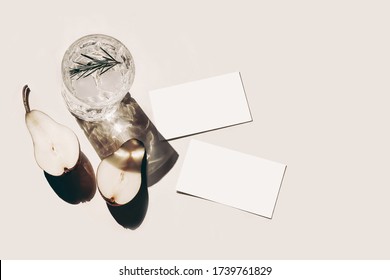 Summer Stationery Still Life Scene. Cut Pear Fruit, Old Cocktail Glass, Alcohol Drink With Ice Cubes, Rosemary Herbs Leaves Isolated On Beige Table Background. Business Cards Mockups. Flat Lay, Top