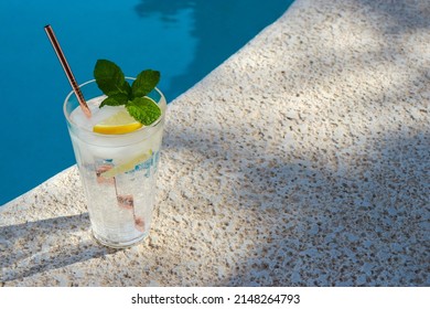 Summer Still Life With A Glas Of Ice Cold Water, Summer Hat, Sunglasses, Sunscreen And Phone On Pool