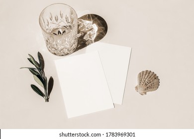 Summer Still Life. Glass Of Water, Cocktail With Long Shadows, Sea Shellt And Olive Tree Branch On Beige Table Background In Sunlight. Blank Greeting Card Mockup. Flat Lay, Top View. Birthday Concept.