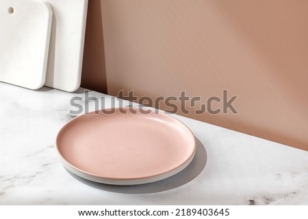 Summer still life scene with empty blank pink plate, marble boards. Eco minimalist mockup with window shadow. Tableware set. Front diagonal view
