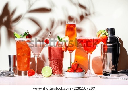 Summer strawberry alcoholic cocktails, mocktails, smoothies and shakes with fruits and berries in glasses. Refreshing cold drinks. Beige pink vanilla background, hard light, shadow pattern