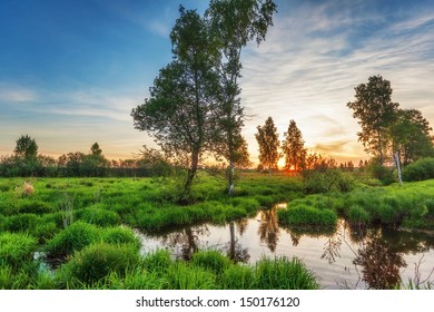 Summer sunset around field with with small river