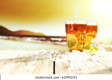 Summer sunset on beach and photo of ice tea on desk with ice and free space for your decoration