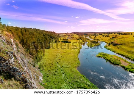 summer sunset over the river and forest. beautiful view from a cliff to a river with islands and a shore with young green grass