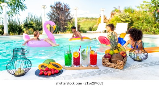 Summer Swimming Pool Party! Happy Multiracial Group Of Friends Relaxing On Inflatable Mattress Having Drinks Celebrating Hot Holidays Outdoor. People Having Cocktails On Happy Hour. Lifestyle Concept