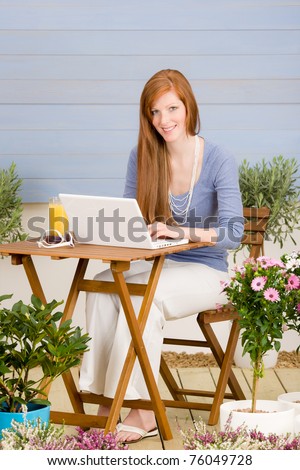 Summer terrace redhead woman with laptop in garden