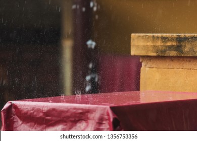 Summer Terrace Of The Restaurant In The Rain. Wet The Table With A Burgundy Tablecloth. A Spray Of Water. Rainy Weather.