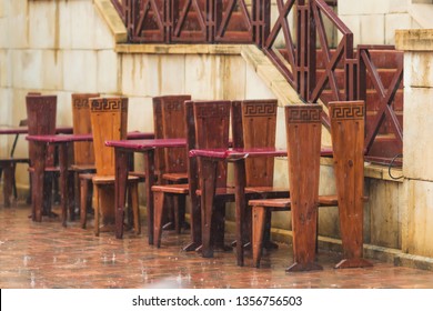 Summer Terrace Of The Restaurant In The Rain. Wet Burgundy Chairs . A Spray Of Water. Rainy Weather.