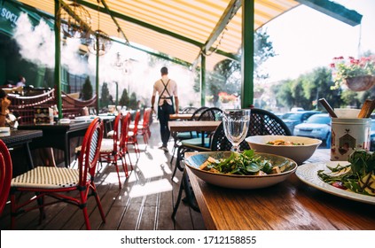 Summer terrace table with dishes and glass waiter on the background, horizontal format