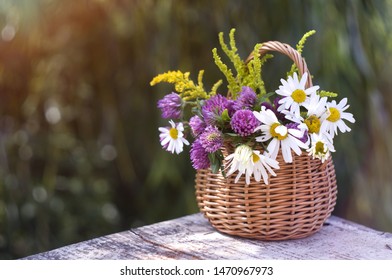 summer theme: basket with wildflowers on a blurred background - Shutterstock ID 1470967973