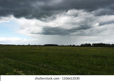 Summer thunderstorm over the meadow. Thunderous sky. The rain is pouring from the cloud, the storm is coming.