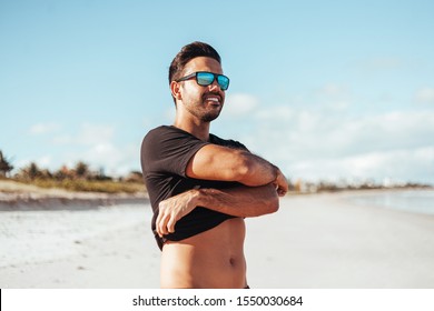 Summer Time. Smiling Man Taking Off His Shirt At The Beach