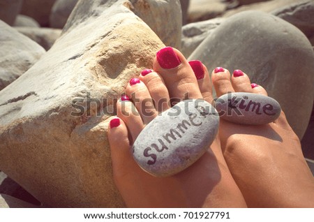 Summer time vacation. Sea travel concept. Pebbles with inscriptions  "summer time" on female feets on the sea beach.