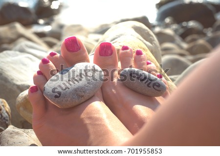 Summer time vacation. Sea travel concept. Pebbles with inscriptions  "summer time" on female feets on the sea beach.