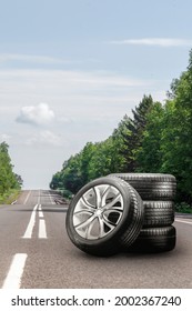summer tires and alloy wheels set on an asphalt road. tire change season, auto trade, copy space, square photo. auto tuning and tire service