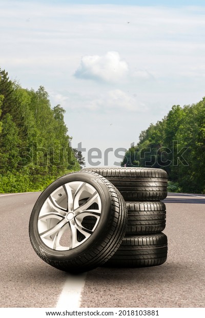 summer tires and alloy wheels set on an asphalt\
road. tire change season, auto trade, copy space , auto tuning and\
tire service. vertical\
photo