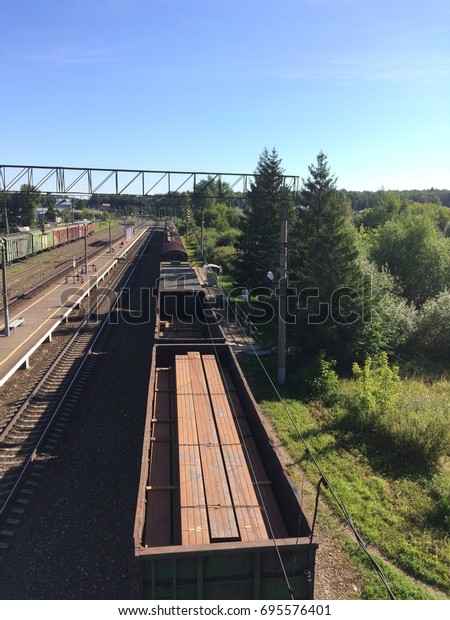 Summer train paths and green trees and industrial\
train cars