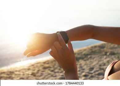 Summer Training. Close Up View Over The Shoulder Of Sportive Lady Checking Her Smart Watch On Wrist, Sun Flare Light