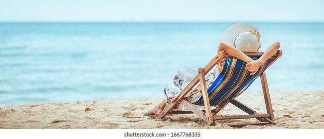 Summer Travel Beach Vacation Concept, Traveler Asian Woman With Hat And Dress Relax On Chair Beach At Pattaya, Chon Buri, Thailand