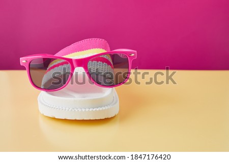 Summer travel concept. Flip flops or slippers and sunglasses on pastel background. Beach accessories.