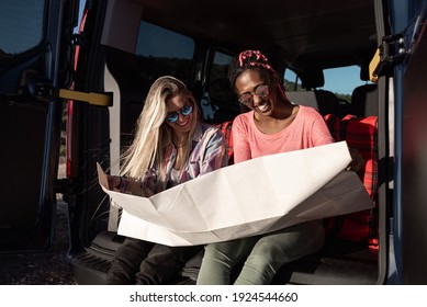 Summer travel concept - Multiracial young friends looking at map to plan a camper van trip - Focus on african girl - Powered by Shutterstock