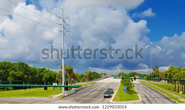Summer travel in Florida by car, view from\
above, two long highway straight roads with crossroad, coconut\
palms on both sides, cars, power pylons, sunny sky with beautiful\
clouds in the background