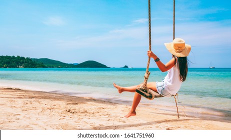 Summer travel vacation concept, Happy traveler asian woman with white vest, hat and shorts Jeans relax on swing in tropical beach, Koh mak, Thailand - Powered by Shutterstock