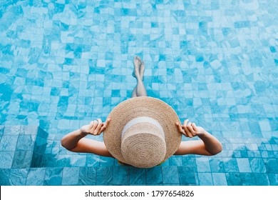 Concepto de vacaciones de verano, viajera feliz mujer asiática con sombrero y bikini relajarse en un lujoso hotel con piscina de borde infinito de día en Phuket, Tailandia