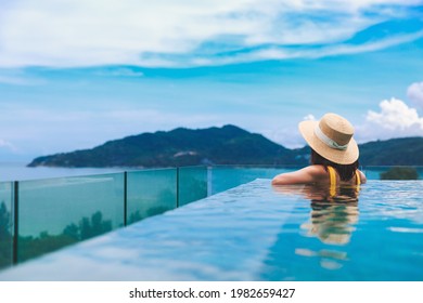 Summer travel vacation concept, Happy traveler asian woman with hat and bikini relax in luxury infinity pool hotel resort at day in Phuket, Thailand - Shutterstock ID 1982659427