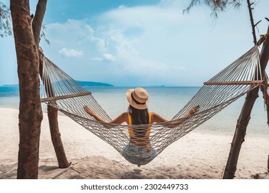 Summer travel vacation concept, Happy traveler asian woman with hat relax in hammock on beach in Koh Rap, Samui, Surat Thani, Thailand - Powered by Shutterstock