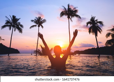 Summer travel vacation concept, Silhouette traveler asian woman with bikini relax in luxury infinity pool hotel resort with sea beach and palm tree background at sunset in Koh Kood, Thailand