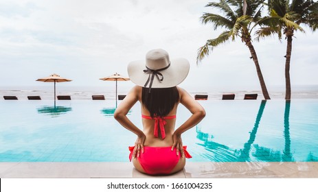 Summer Travel Vacation Concept, Traveler Asian Woman With Bikini And Hat Relax In Infinity Pool In Luxury Hotel Resort With Sea Beach Background At Thailand